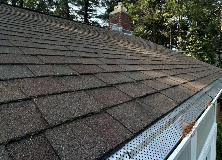 Close-up of asphalt shingle roof with gutter guard along the roof edge in Boston, MA.