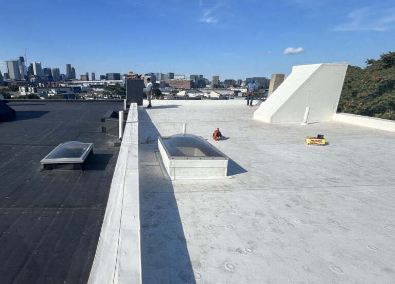 Flat commercial roof with white membrane and skylight during roof inspection in Boston, MA.