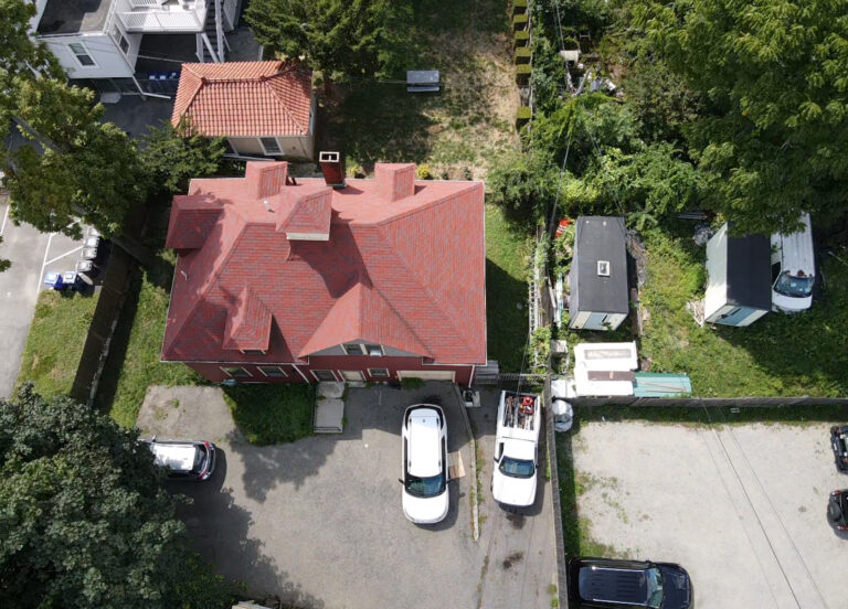 Aerial drone view of a red roofing system on a residential property during roof inspection in Boston, MA.