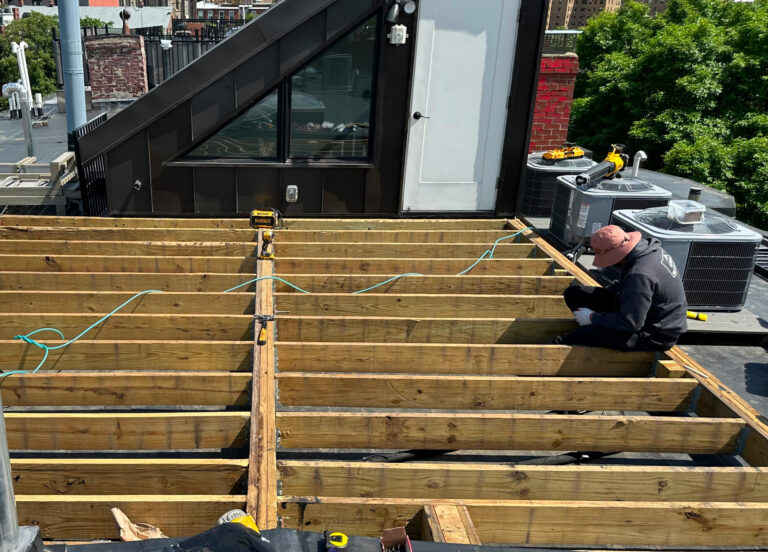 Contractor installing deck framing and joists during exterior construction in Boston, MA.