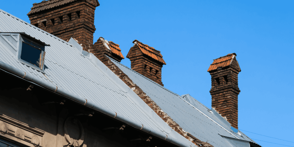 roof installation problems shown with multiple brick chimneys on corrugated metal roof needs roof repair