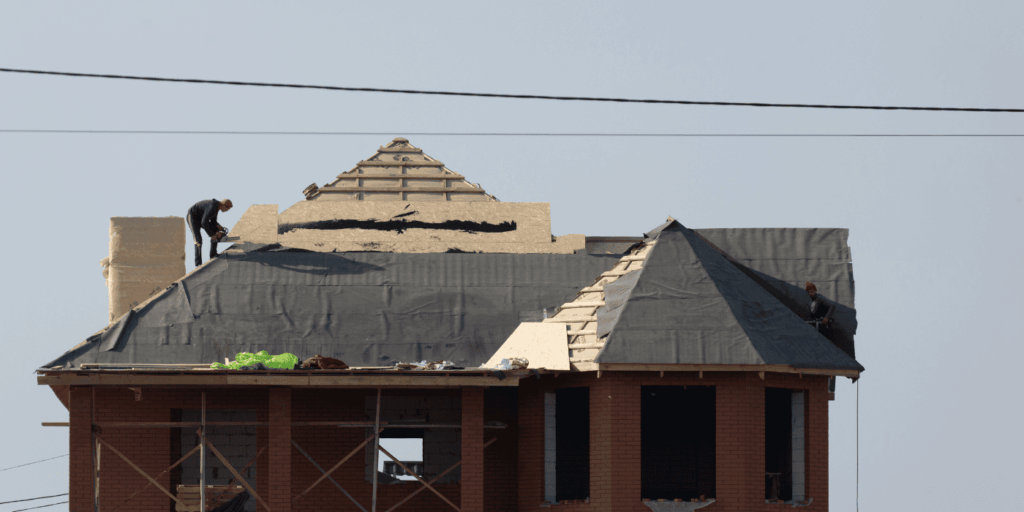 roof installation in progress with exposed underlayment and workers fixing roofing issues on home