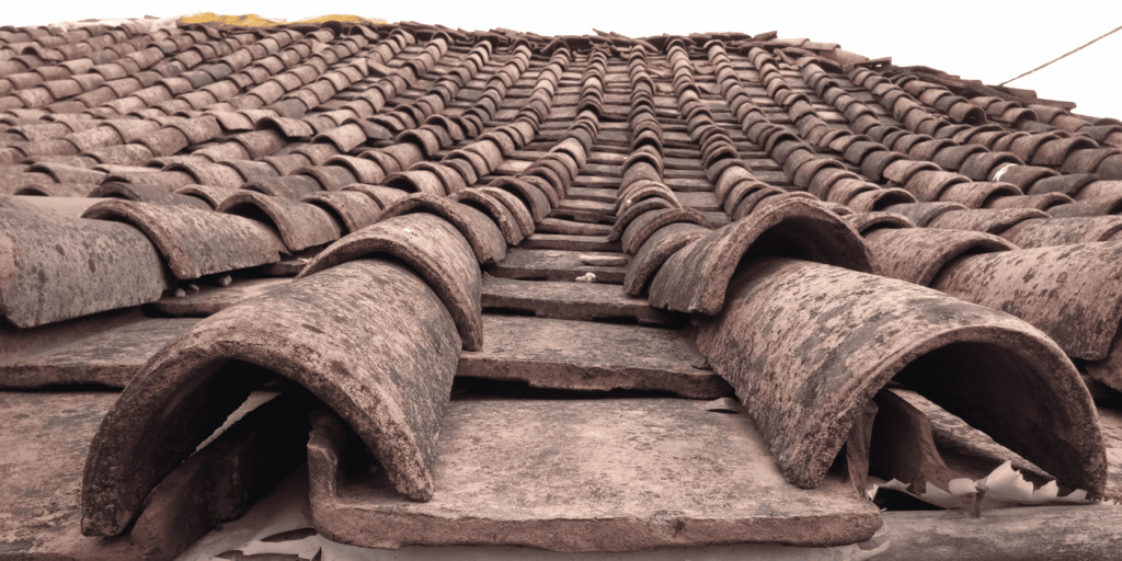 image with close-up of aged clay tile roof showing poor roof installation with weathered & displaced tiles