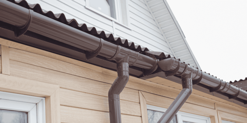Brown half-round gutter material with matching downspout on home exterior displaying classic gutter types