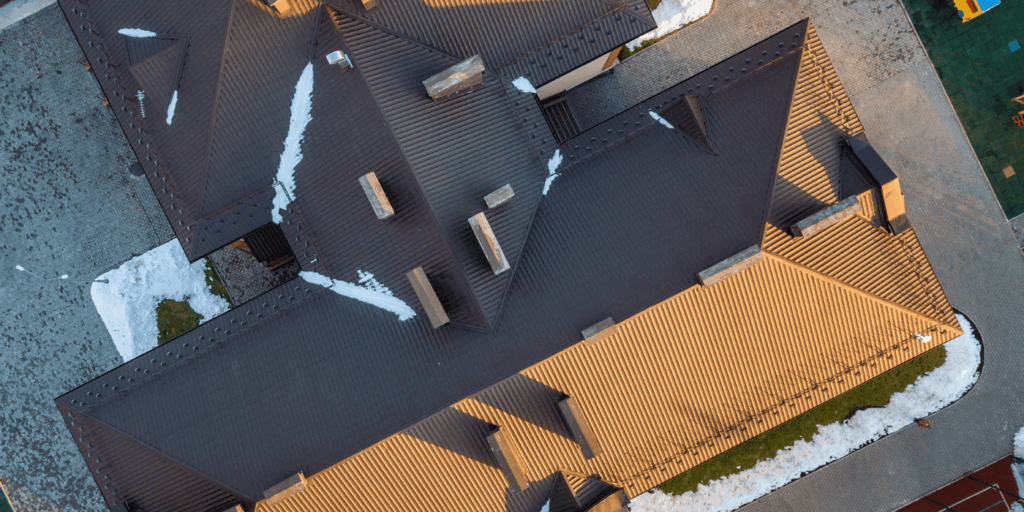 Aerial view of a large residential roof with light snow, inspected under 4 balls rule roofing guidelines