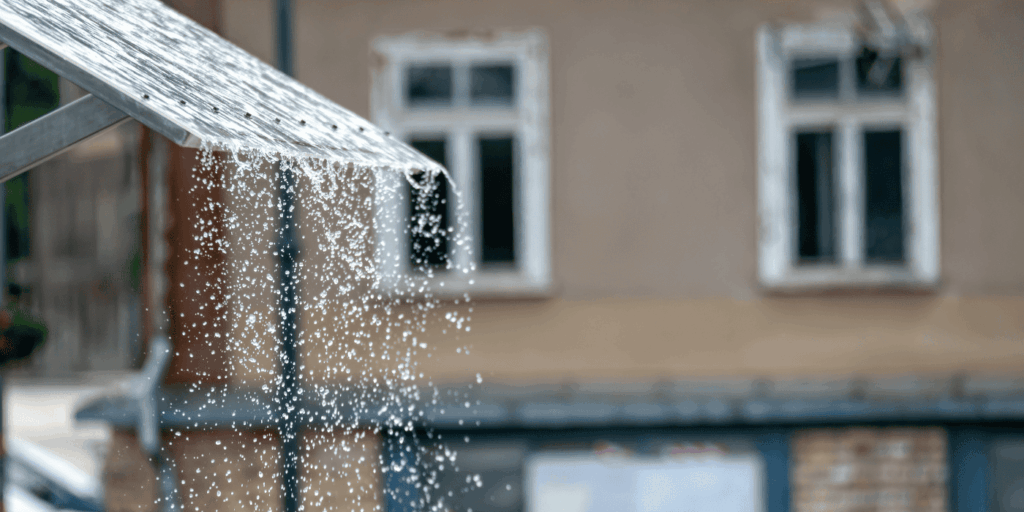 Water dripping from a metal gutter during rain, showing an active roof leak that needs quick inspection and repair
