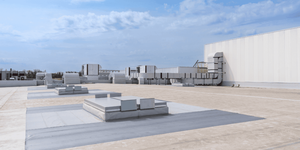 FInal result of large commercial flat roof with HVAC units and drainage systems under clear sky