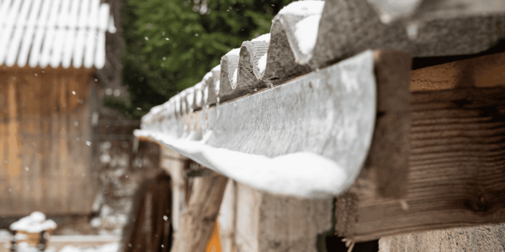 Snow collecting along a roof edge and gutter, showing why roof care in winter helps prevent ice buildup