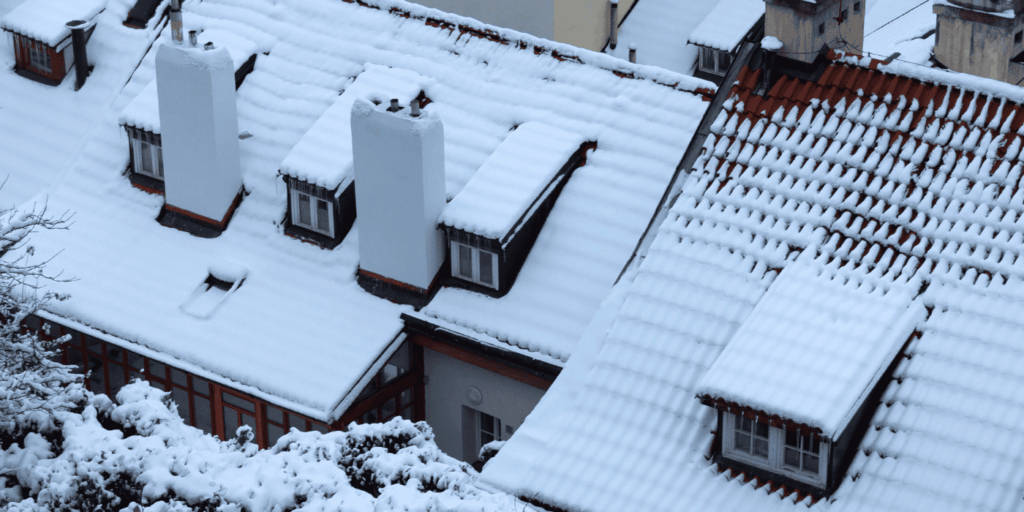 Residential rooftops covered in heavy snow, highlighting the importance of roof care in winter