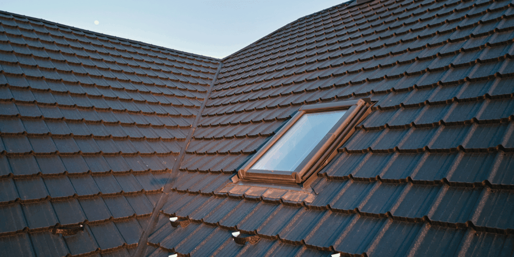 Modern roof with skylight after roof repair, showing clean shingle alignment and proper sealing around the window.
