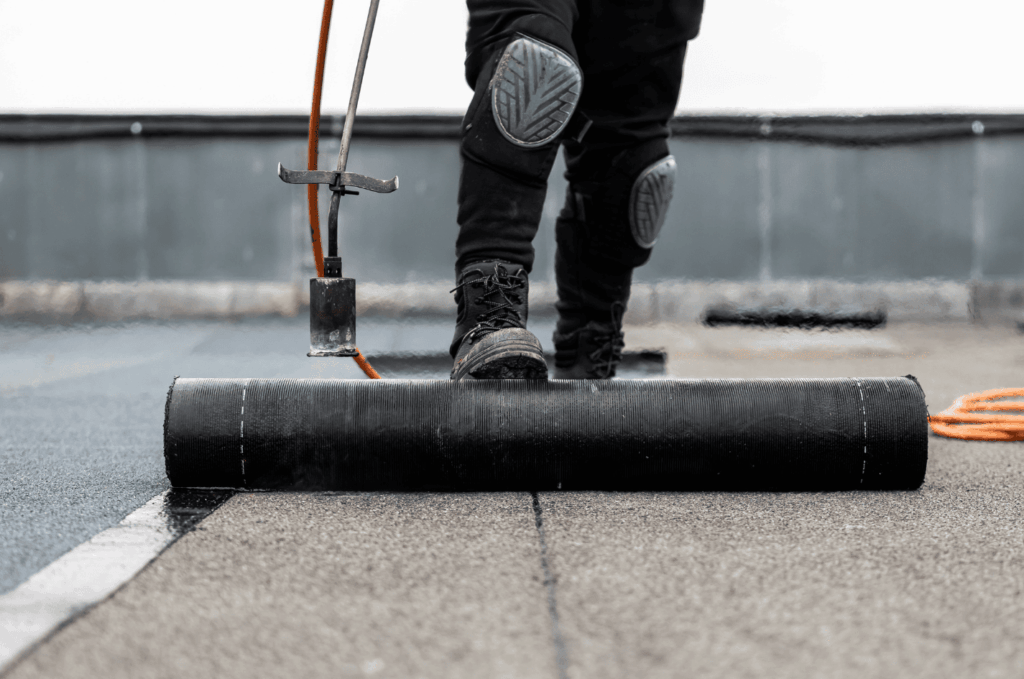 Worker installing waterproof membrane during a professional flat roof repair project.