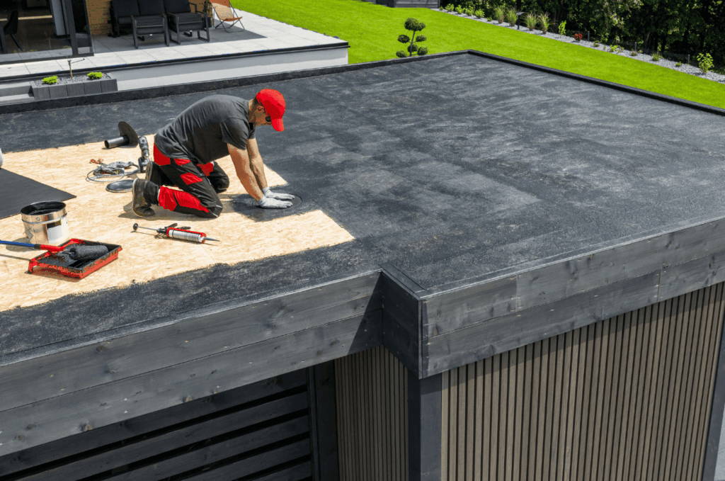 Contractor performing flat roof repair on a modern home, sealing and fixing damaged roofing surface.