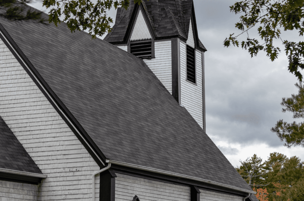 Historic style building with a steep shingle roof after careful roof replacement that improves durability and curb appeal.