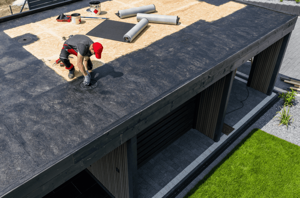  Worker installing durable flat roof materials on a modern building to create a strong waterproof surface for long-term protection.