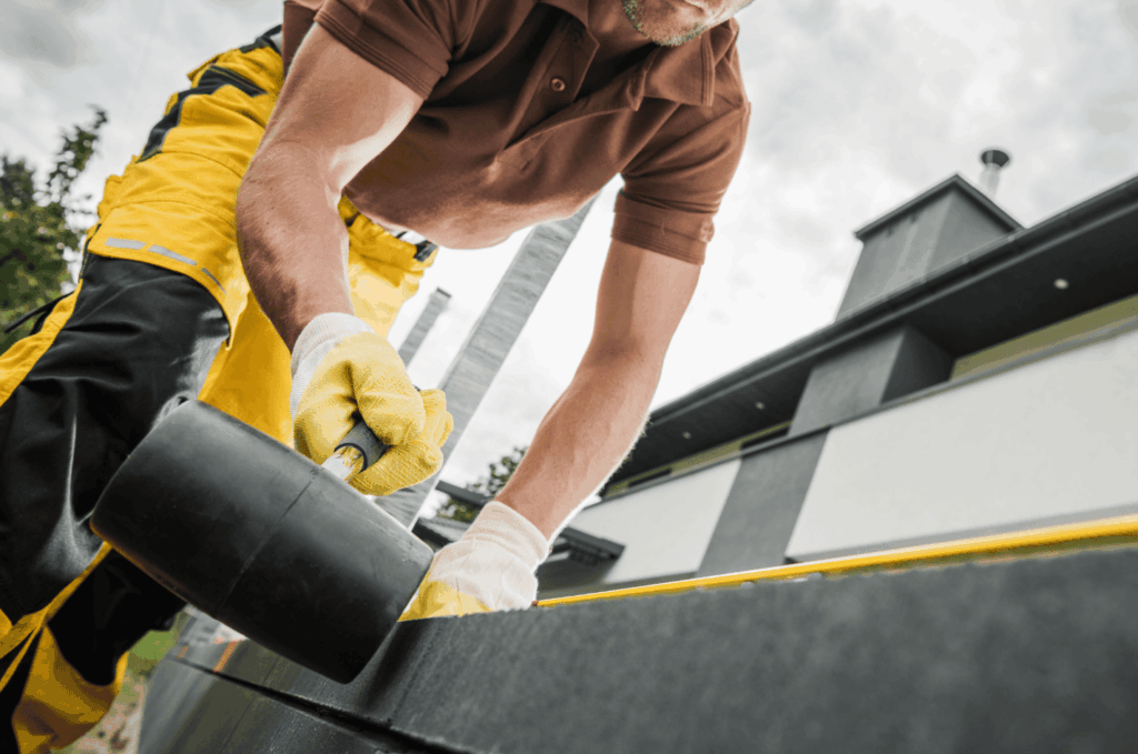 Contractor sealing edges with specialized flat roof materials to protect the roof from leaks, rain, and changing weather.