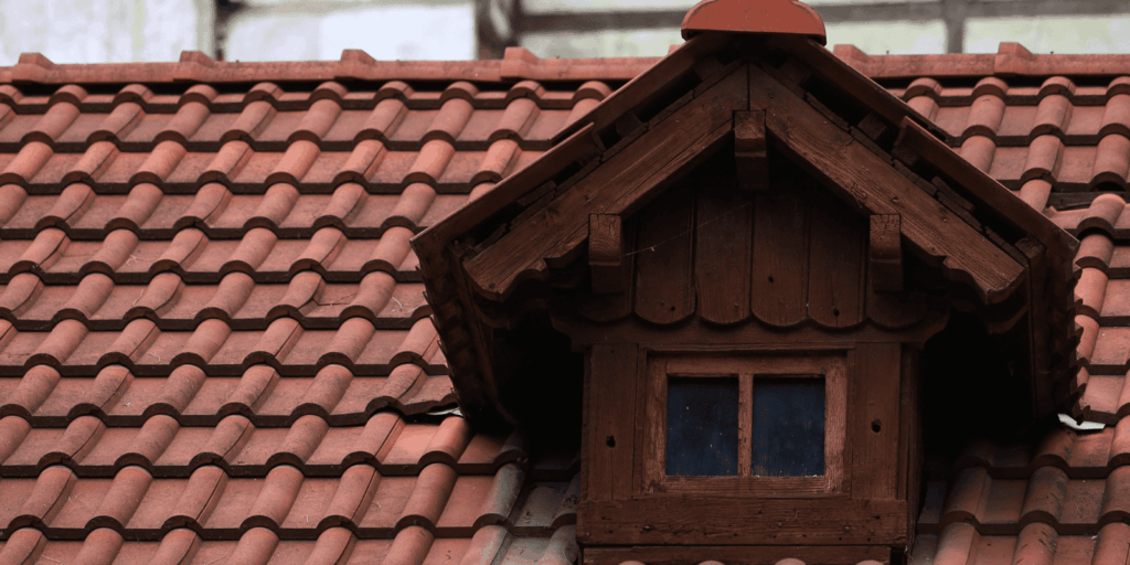 Home roof with traditional tile roofing and dormer window, showing a durable design that adds style and reliable coverage