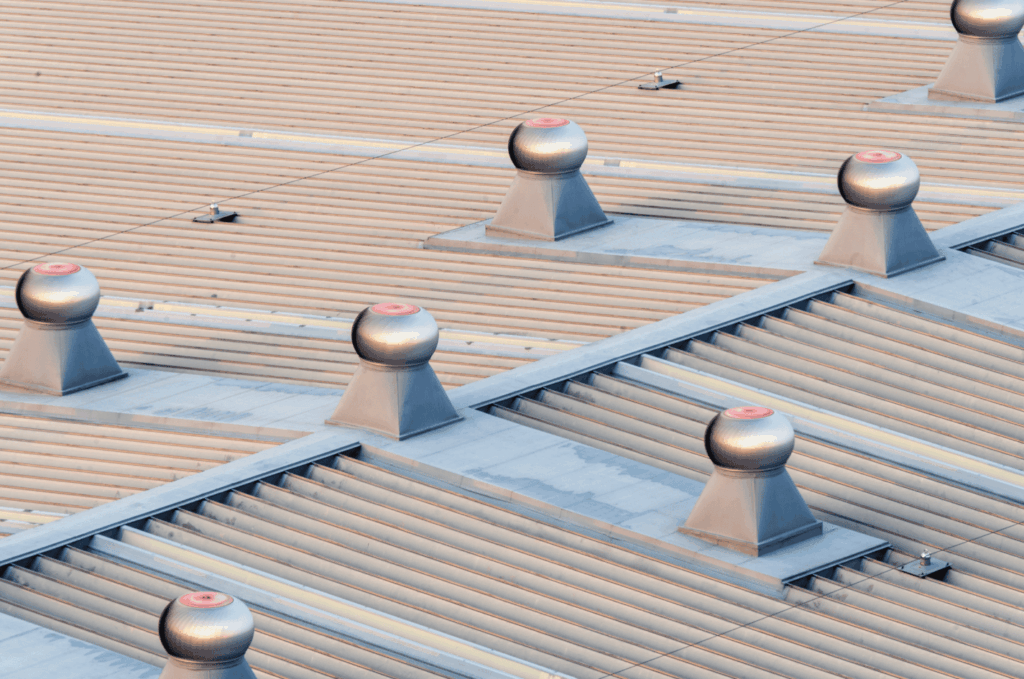 Metal commercial roof with multiple ventilation units installed in neat rows for airflow and proper building ventilation