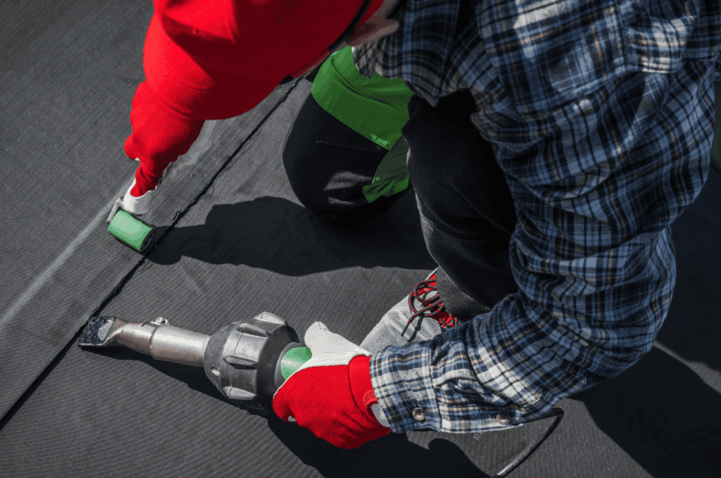 Close-up of a contractor sealing seams on rubber roofing using a heat tool to create a strong, waterproof bond.