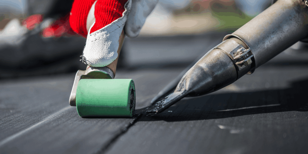 Detailed view of rubber roofing seam being pressed with a roller to ensure tight sealing and long-lasting protection.