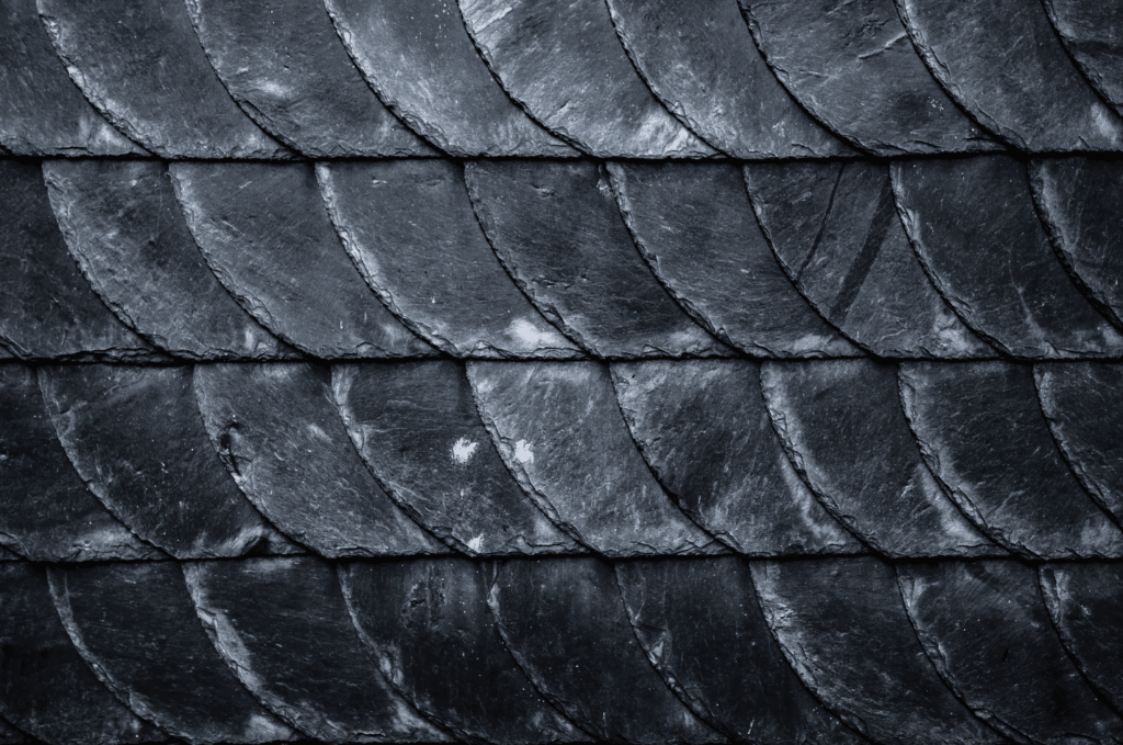 Close-up of dark slate roofing tiles installed in overlapping rows, creating a strong and long-lasting protective roof surface