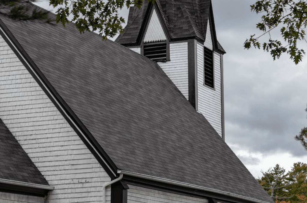 Church building roof with steep shingles shown during a roof inspection to check roof slopes and overall shingle condition