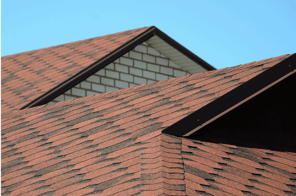 Red asphalt shingle roof ridge viewed during a roof inspection to check alignment, flashing, and signs of wear