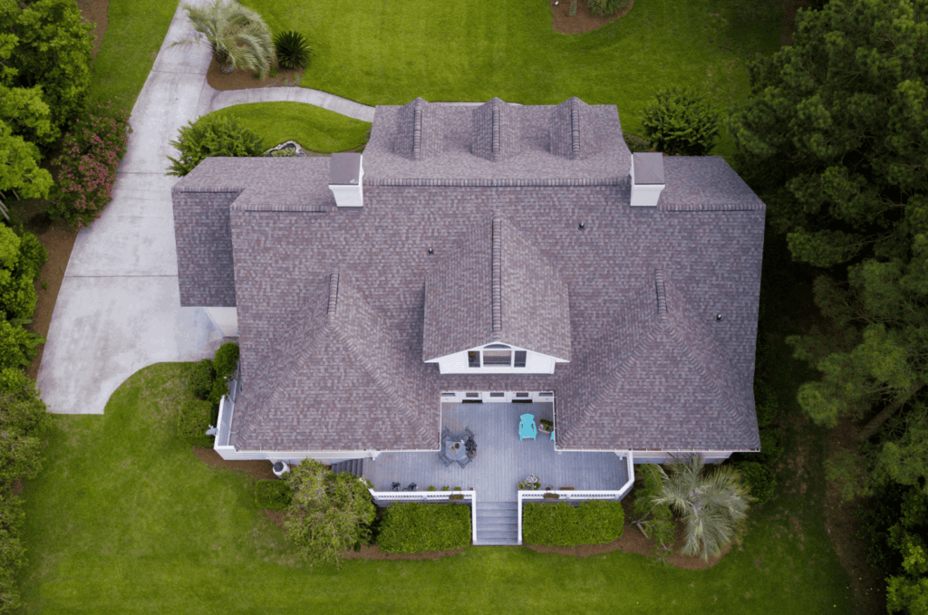 Aerial view of a home surrounded by trees during a drone roof inspection to review shingles and roof structure