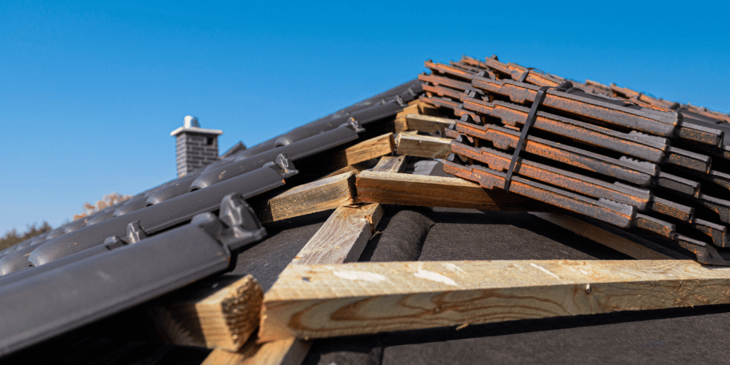 Close view of roof installation showing wooden framing and stacked roof tiles ready for placement and sealing