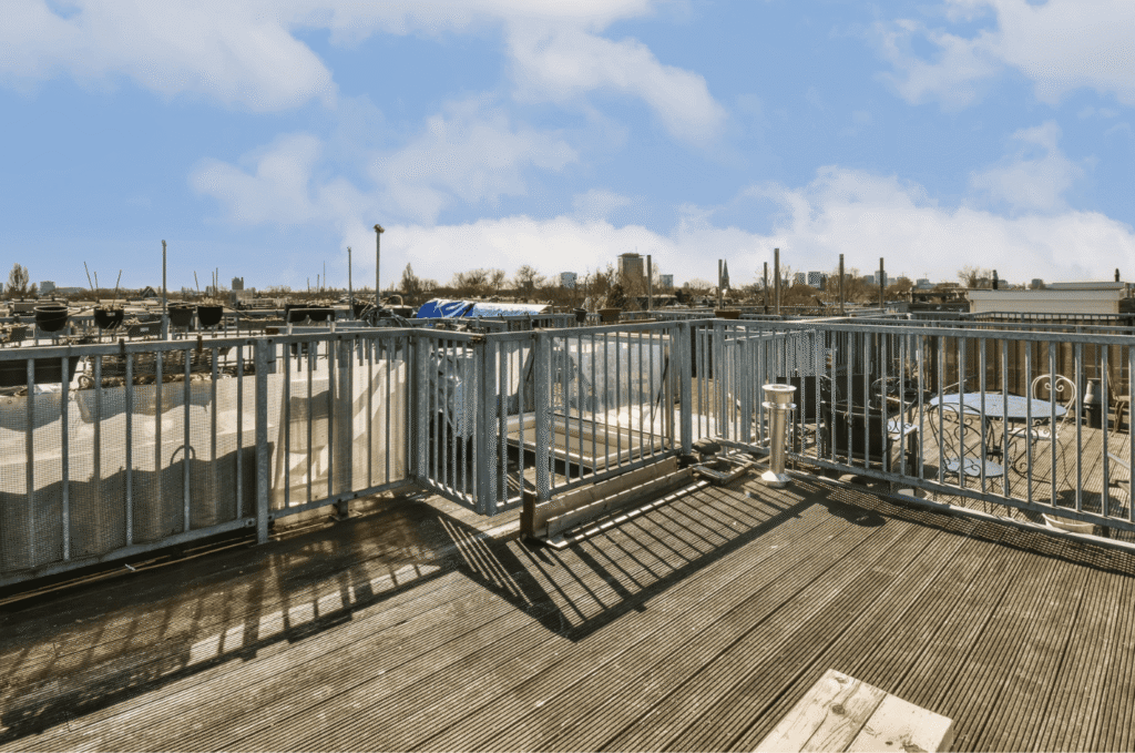 Urban roof deck install featuring metal railings, rooftop seating space, and wide skyline views under blue skies