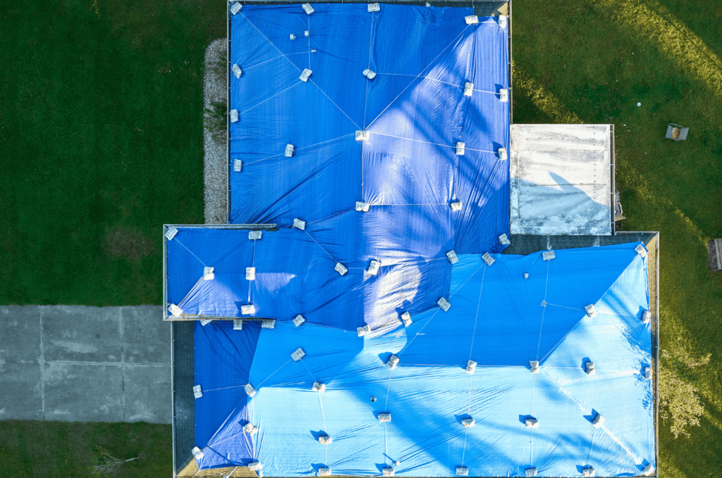 Blue roof underlayment covers a large home roof to protect it from rain and weather during roof replacement work 