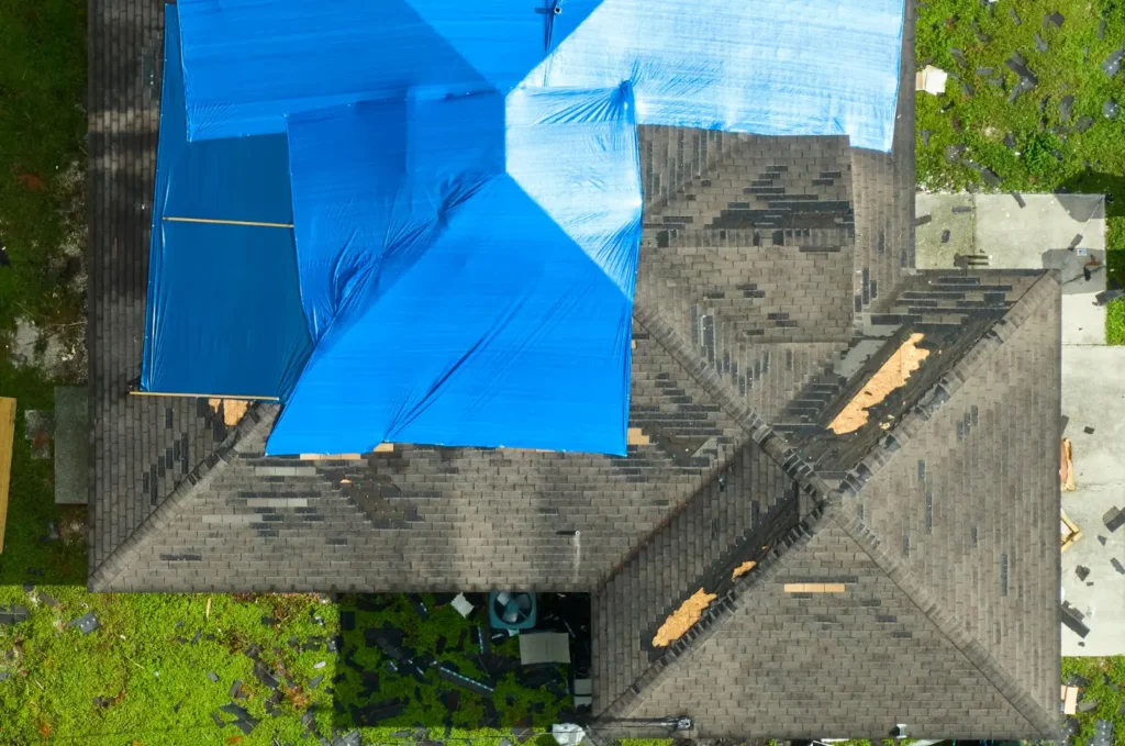 Aerial view of roof tarping covering storm damaged shingles to protect the home from rain and further damage