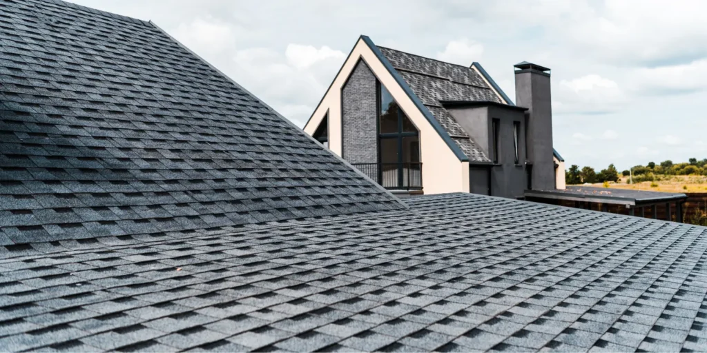  Well-maintained asphalt shingle roof surrounded by garden showing how regular care can help extend roof life.