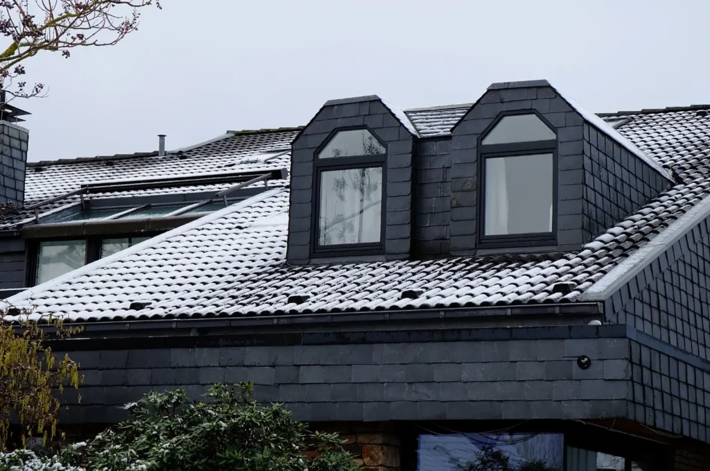 Snow-covered roof with dormer windows, a common area where emergency roof repair may be needed after winter storms