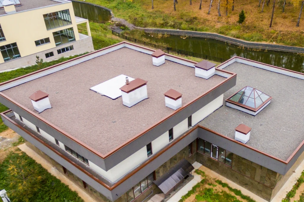 A flat roof drainage outlet is visible on the roof surface beside pooled rainwater