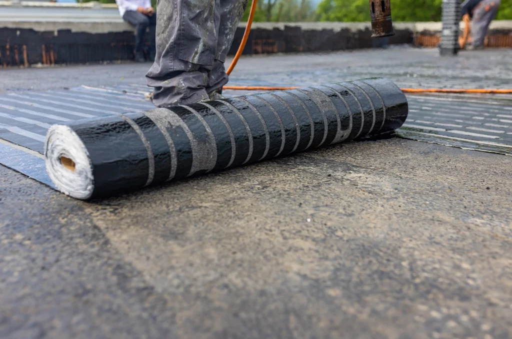 Modified bitumen roof material applied in overlapping layers across a flat roof